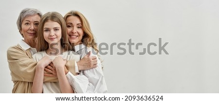 Smiling caucasian family of three female generations hugging and looking at camera. Age and generation concept. Family relationship and closeness. Isolated on white background Studio shoot. Copy space
