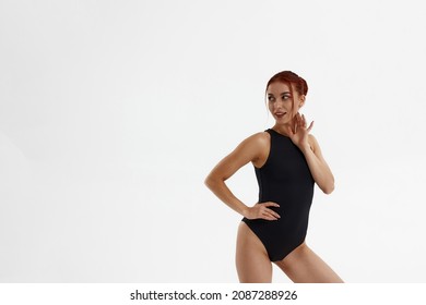 Smiling caucasian female ballet dancer standing and looking away. Young slim beautiful woman with red hair and wearing leotard. Girl isolated on white background. Studio shoot. Copy space