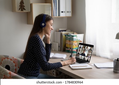 Smiling Caucasian female employee in headphones sit at desk at home talk on video call with colleagues, young woman have online webcam conversation virtual event with diverse multiethnic coworkers - Shutterstock ID 1784830964