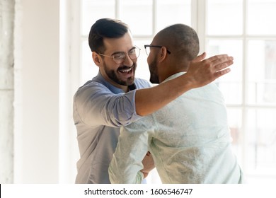 Smiling Caucasian man in glasses feel overjoyed meeting ethnic male friend or colleague, happy young multiethnic guys hug embrace tapping shoulder excited encounter at party, friendship concept - Powered by Shutterstock