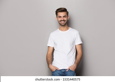 Smiling Caucasian man wearing casual clothes stand isolated on grey studio background look at camera posing, happy male model actor in white t-shirt hold hands in pockets shooting casting - Shutterstock ID 1531440575