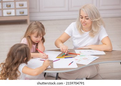 Smiling caucasian mom   two daughters draw together sitting the floor in the living room  Happy family concept 