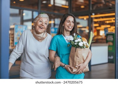 A smiling Caucasian nurse aids an elderly woman carrying a grocery bag, embodying support and assistance outside a supermarket. - Powered by Shutterstock