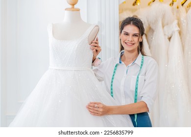 Smiling caucasian woman is bridal shop owner tidying up the wedding dress and looking at camera at wedding studio, Small business entrepreneur wedding planner and tailor designer concept - Shutterstock ID 2256835799