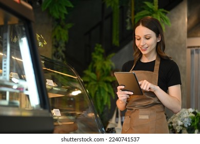 Smiling caucasian woman coffee shop owner using digital tablet to receiving online orders - Powered by Shutterstock