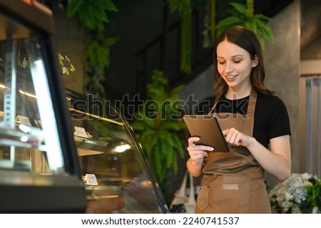 Smiling caucasian woman coffee shop owner using digital tablet to receiving online orders