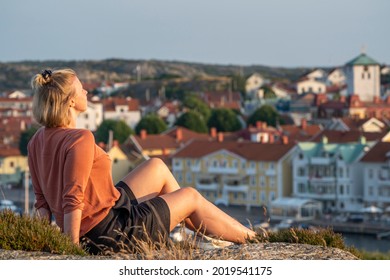 Smiling Caucasian Woman sunlit Enjoying Sunset over Swedish Summer party Island and Village Marstrand, Near Gothenburg and Sweden West Coast.