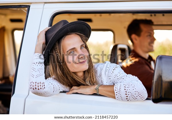 Smiling Caucasian woman, traveler on road trip with\
husband,get out of camping van window in the morning. Cosy\
comfortable setup in camper van. Millennial travel trend, adventure\
on the road.