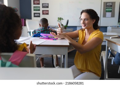 Smiling caucasian young female teacher talking to african american girl in sign language. unaltered, education, childhood, learning, teaching, disability and school concept. - Powered by Shutterstock