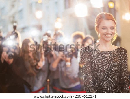 Smiling celebrity at event with photographing paparazzi in background