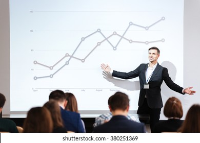 Smiling charismatic speaker giving public presentation in conference hall - Powered by Shutterstock