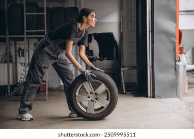 Smiling Charming Woman Car mechanic holding tire at repair garage. Replacement of winter and summer tires.

 - Powered by Shutterstock