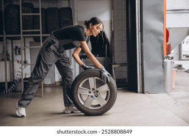 Smiling Charming Woman Car mechanic holding tire at repair garage. Replacement of winter and summer tires.

 - Powered by Shutterstock