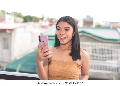 A Smiling And Chatty Filipina Teenager Video Calls Her Parents Who Are Working Abroad. A Beautiful Millennial Woman Calls Her Friends Online On Her Cellphone Early In The Morning.