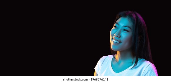 Smiling, Cheerful. Asian Young Woman's Portrait On Dark Studio Background In Neon Light. Beautiful Female Model In Casual Style. Concept Of Human Emotions, Facial Expression, Youth, Sales, Ad. Flyer