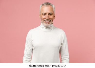 Smiling Cheerful Attractive Elderly Gray-haired Mustache Bearded Man Wearing Casual Basic White Turtleneck Standing And Looking Camera Isolated On Pastel Pink Color Wall Background Studio Portrait