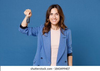 Smiling cheerful beautiful attractive young brunette woman 20s in basic casual jacket standing holding in hand car keys looking camera isolated on bright blue colour wall background studio portrait