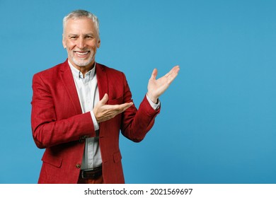 Smiling Cheerful Elderly Gray-haired Mustache Bearded Business Man Wearing Red Jacket Suit Standing Pointing Hands Aside On Mock Up Copy Space Isolated On Blue Color Wall Background Studio Portrait