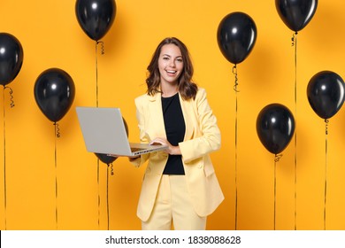 Smiling Cheerful Funny Young Brunette Woman 20s Wearing Basic Light Suit Jacket Using Laptop Pc Computer On Bright Yellow Colour Background With Air Balloons Studio Portrait. Black Friday Sale