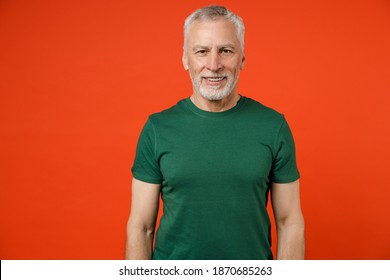 Smiling Cheerful Handsome Attractive Elderly Gray-haired Mustache Bearded Man Wearing Basic Green T-shirt Standing And Looking Camera Isolated On Bright Orange Color Wall Background Studio Portrait