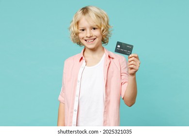 Smiling Cheerful Little Curly Kid Boy 10s Wearing Pastel Pink Shirt Hold In Hand Credit Bank Card Isolated On Blue Turquoise Color Background Children Studio Portrait. Childhood Lifestyle Concept