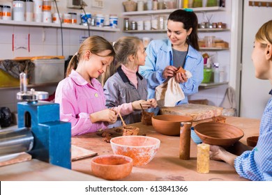 Smiling  Cheerful Positive Schoolgirls Learning From Teacher To Make Ceramics During Arts And Crafts Class