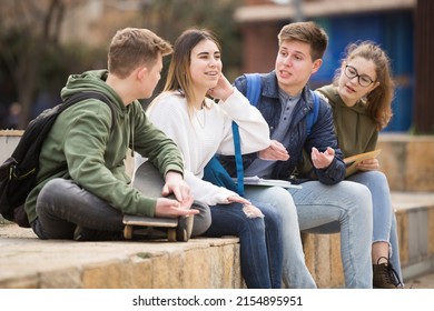 Smiling cheerful teenagers talking with each other sitting on stairs on city street - Powered by Shutterstock