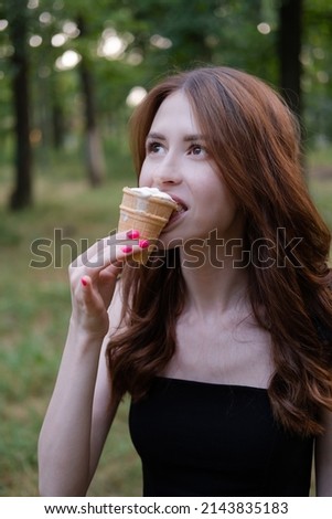 Smiling cheerful ukrainian brunette young woman eating ice cream outdoors.