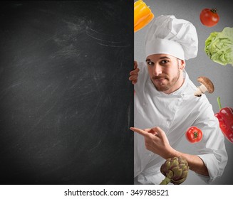 Smiling Chef With Blackboard And Vegetables Background