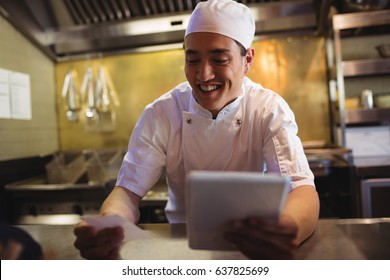 Smiling chef looking at an order list in the commercial kitchen - Powered by Shutterstock