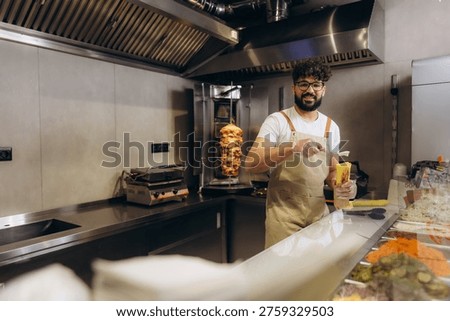 Smiling chef preparing delicious middle eastern fast food on a skewer, working in a modern professional kitchen