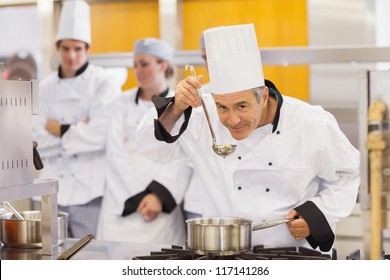 Smiling chef tasting his students work in kitchen - Powered by Shutterstock