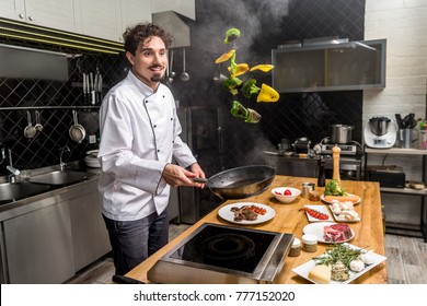 Smiling Chef Tossing Up Frying Bell Peppers With Frying Pan 