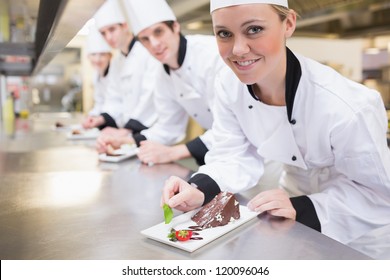 Smiling Chef's finishing dessert plates in the kitchen - Powered by Shutterstock