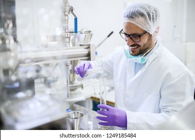 Smiling Chemist Pouring Water Into The Test Tube While Standing In The Lab. Water Quality Check Concept.