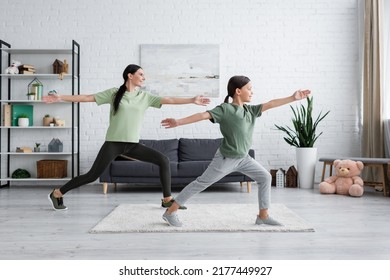 Smiling Child And Babysitter Training In Warrior Pose In Modern Living Room