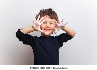 Smiling Child, A Boy In A Black T-shirt Shows His Hands In Soapy Water On A White Studio Background. Hand Disinfection. Soaped Palms And Fingers