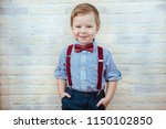 Smiling child boy in fashionable clothes on brick wall background