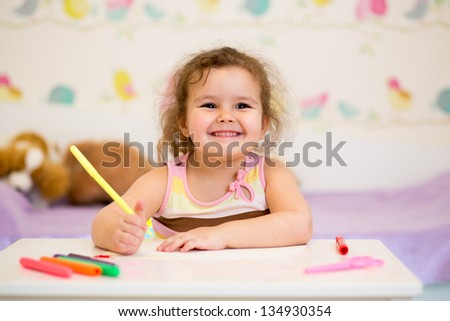 smiling child drawing with felt-tip pen