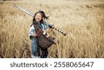 A smiling child in a field holds a large sword and a furry animal in a patterned pouch, exuding an adventurous spirit.