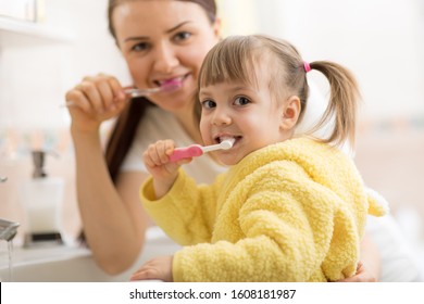 Smiling Child Girl With Her Mom Brushing And Clean Teeth In Bathroom