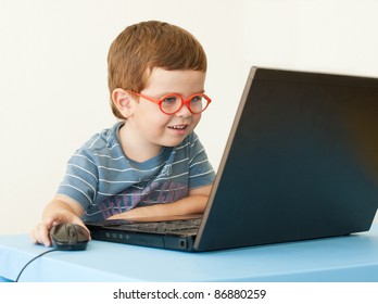 Enfant souriant avec lunettes à l'aide d'un ordinateur