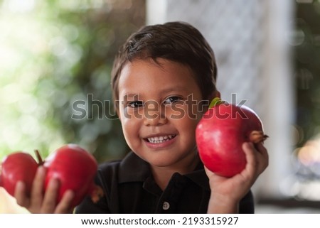 Smiling child holding up in his little hands some freshly cut pomegranates that are grown organically.