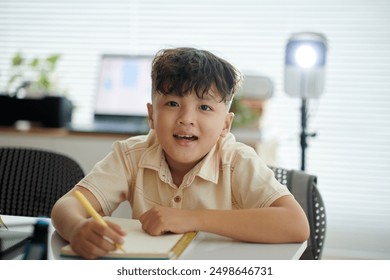 Smiling Child Writing in Modern Home Office Setting - Powered by Shutterstock