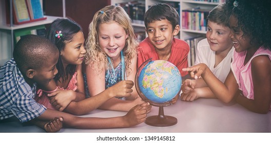 Smiling children with globe on table in library  - Powered by Shutterstock