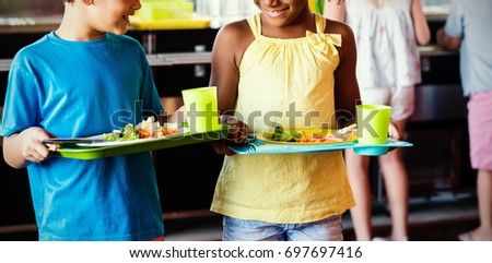 Smiling children holding food tray in canteen at school