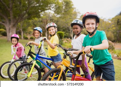 Smiling children posing with bikes in the park
