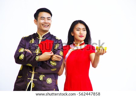 A smiling Chinese man is holding red packet or Ang Pao gift for Chinese New Year. Woman is holding gold ingot.
