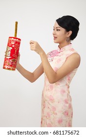 Smiling Chinese Woman Dress Traditional Cheongsam Holding A Big Fire Cracker With Text Greeting For Chinese New Year