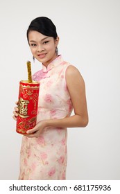 Smiling Chinese Woman Dress Traditional Cheongsam Holding A Big Fire Cracker With Text Greeting For Chinese New Year